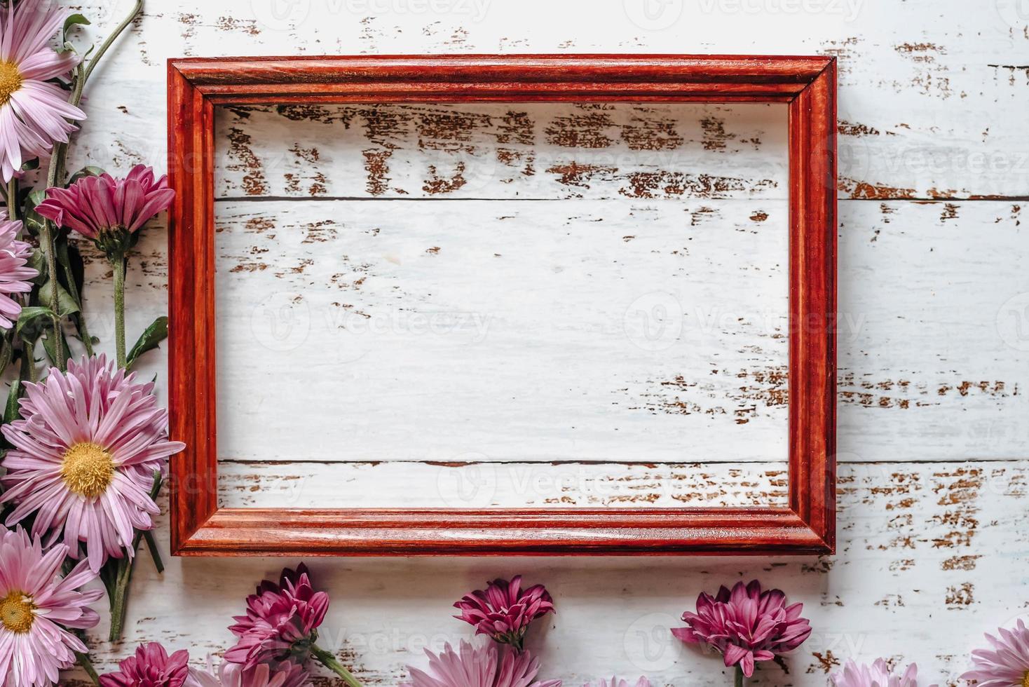 pink chrysanthemums are placed on a white wooden background with space for text and a frame photo