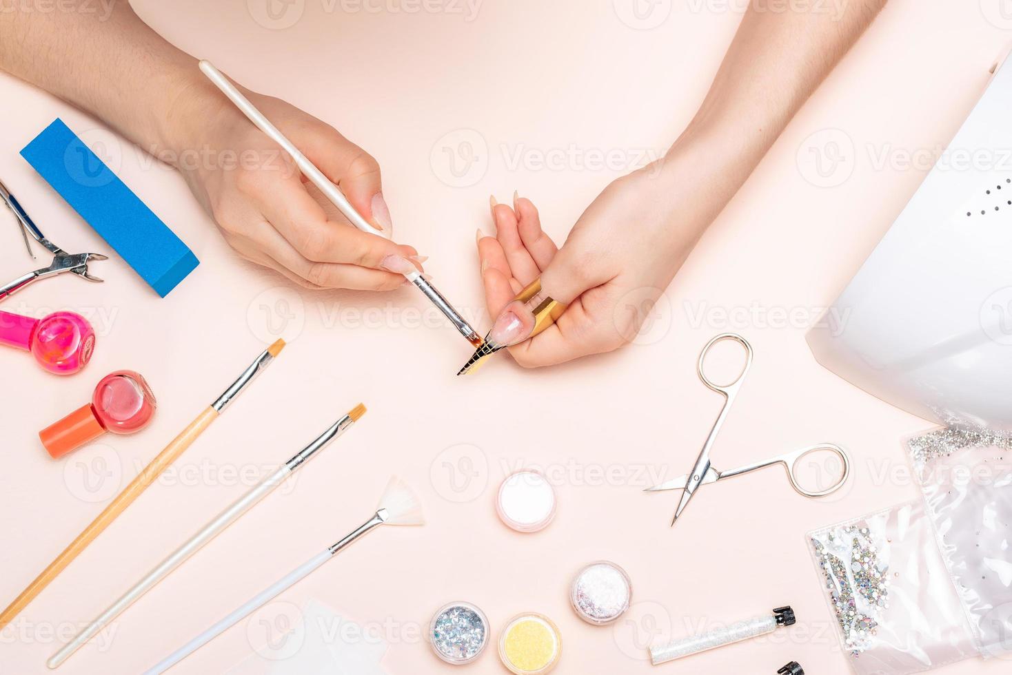 manos de una chica aplicando gel a sus uñas con un cepillo. la vista desde arriba foto