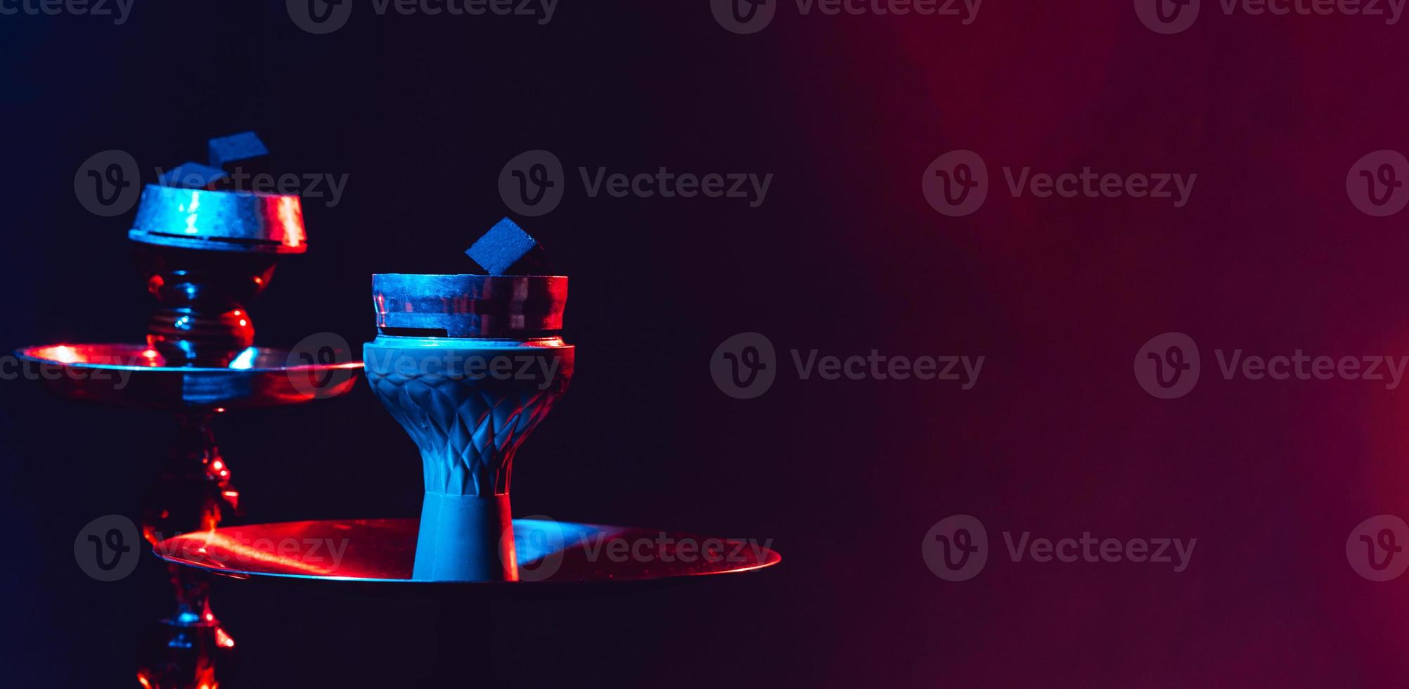 Modern hookah, shisha on a black background with colored lighting and smoke. Close-up and place for your text photo