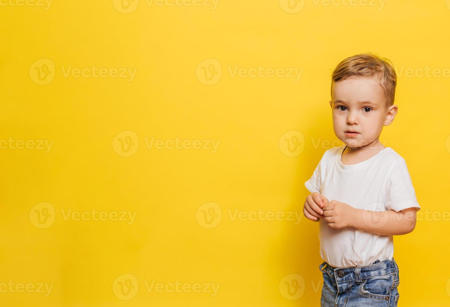 Portrait of a cute laughing little boy on a yellow background. Copy space. photo