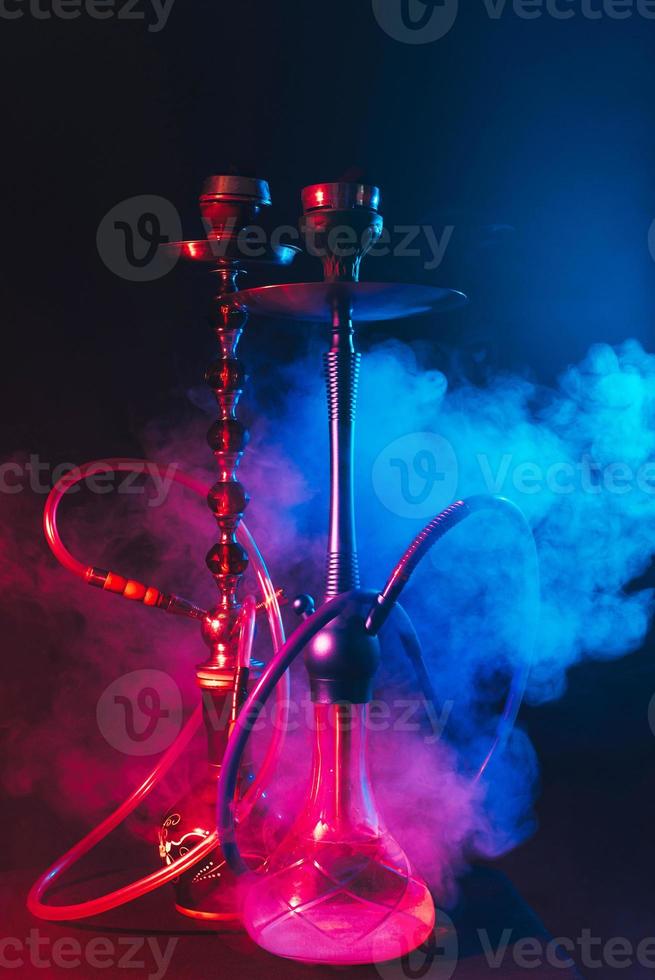 cachimba moderna, shisha sobre un fondo negro ahumado con luces de neón foto