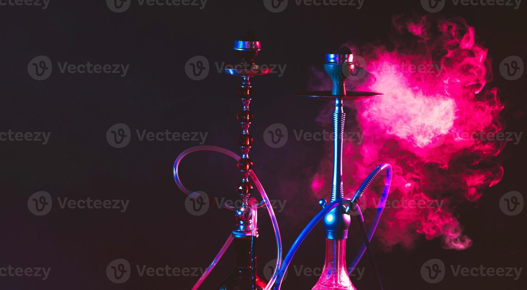Modern hookah, shisha on a smoky black background with neon lighting and smoke. Place for your text photo