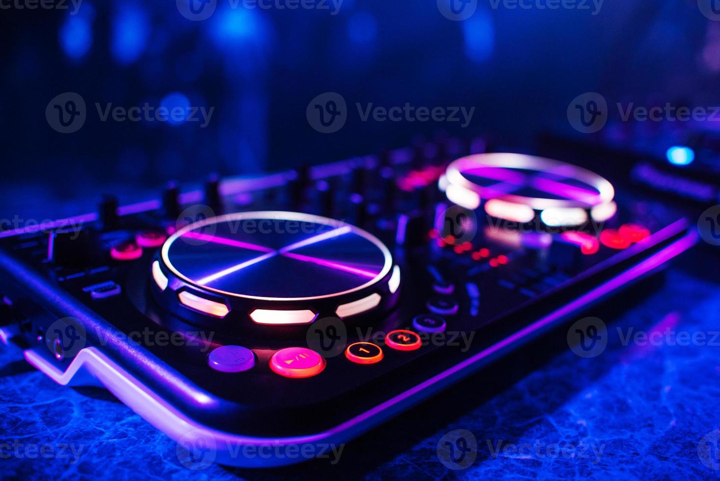 consola de dj para mezclar música con gente borrosa bailando en una fiesta de discoteca foto