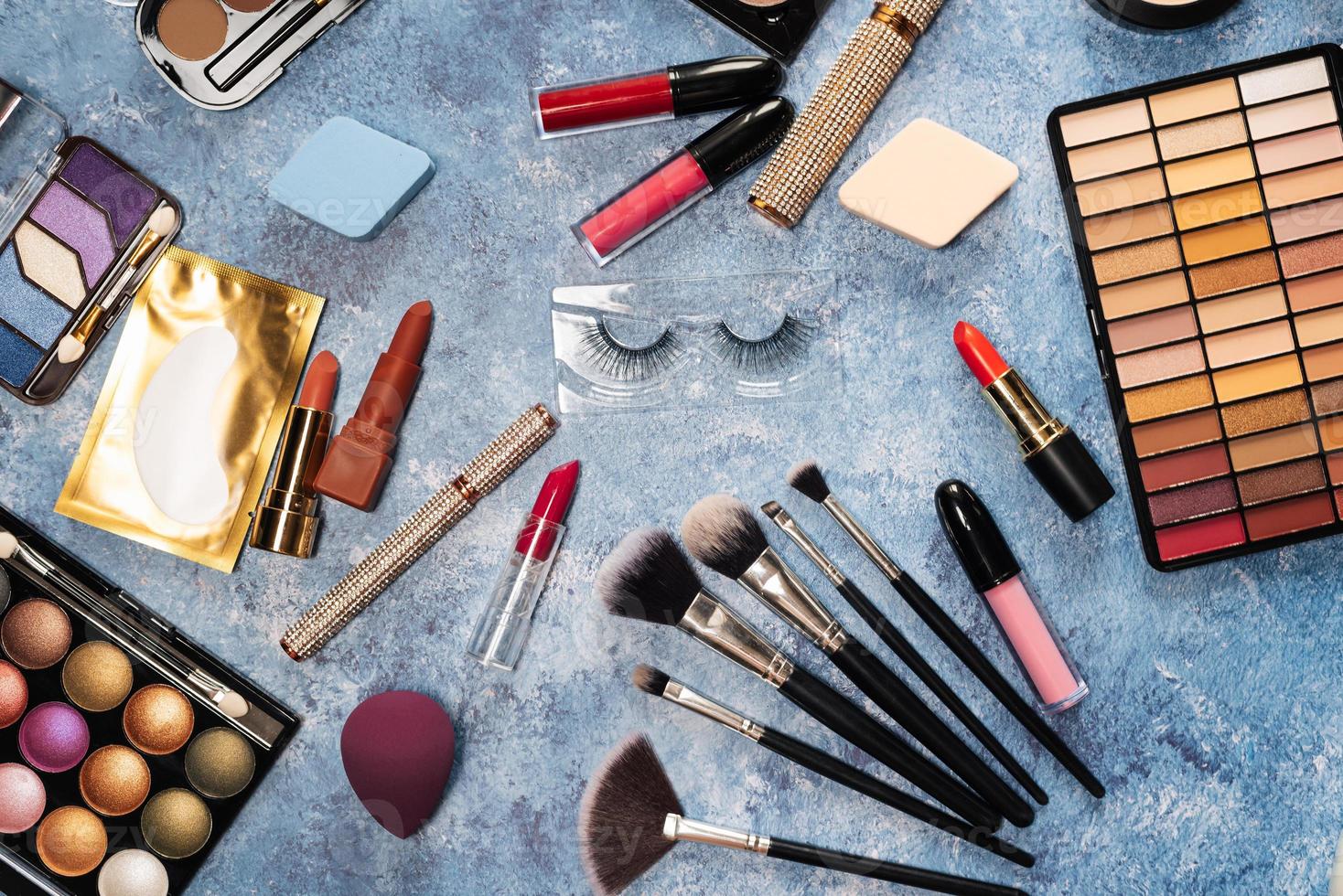 makeup brushes, decorative cosmetics, false eyelashes on a blue background. the view from the top photo