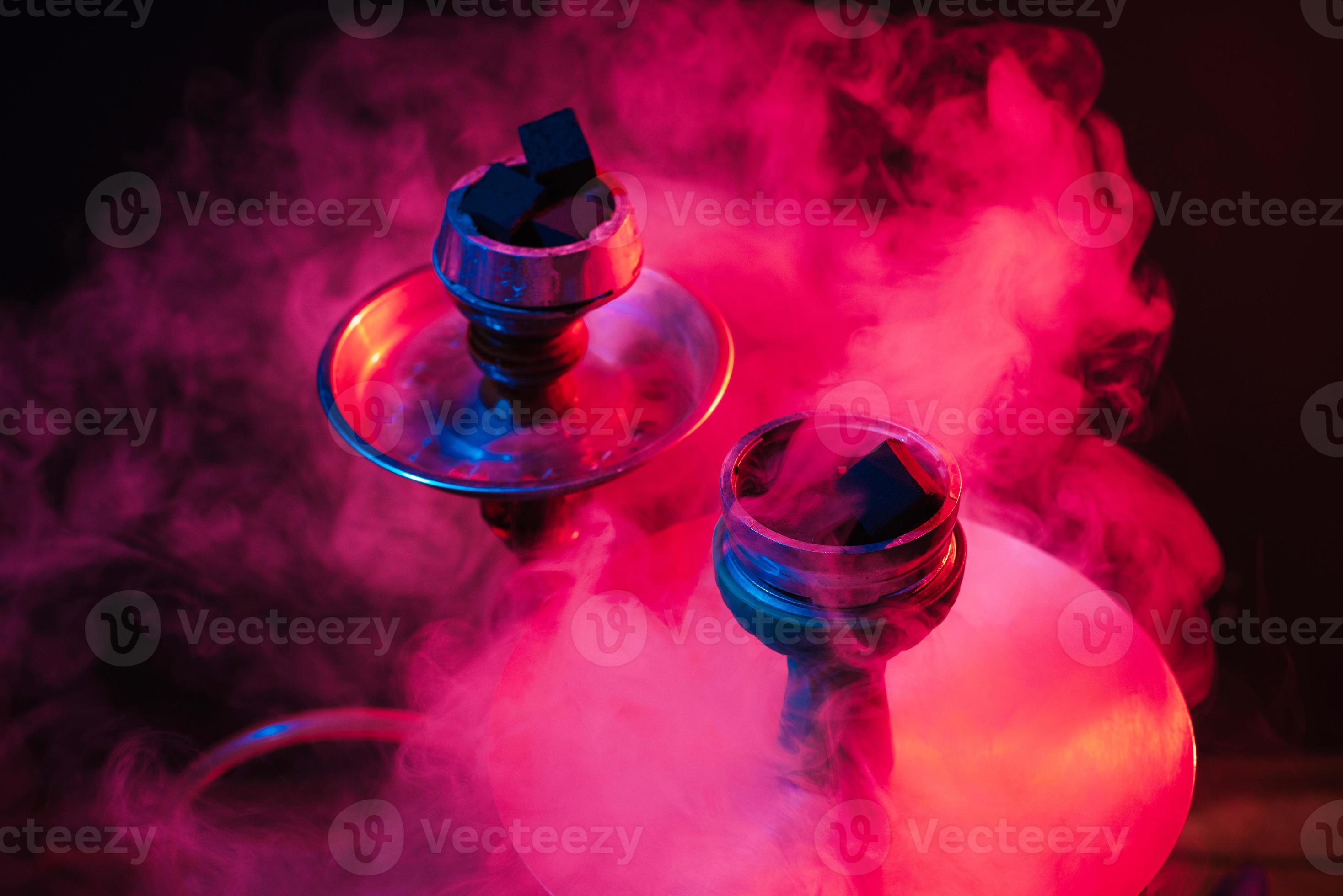hookah bowl, shisha and coals closeup on a smoky black background with colored lighting