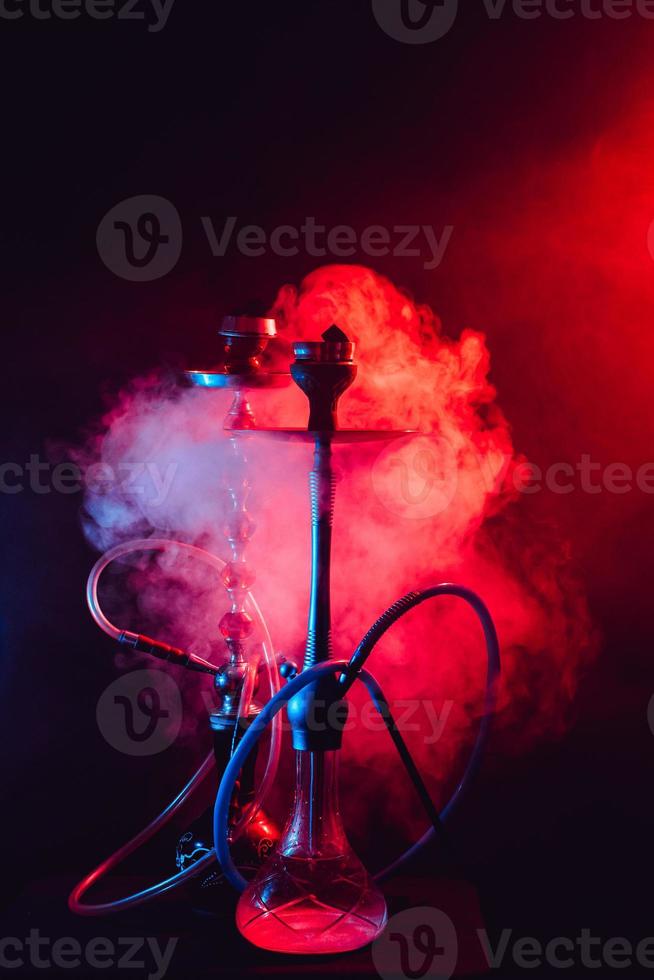 Fashionable hookah with a cloud of smoke on a black background with red and blue glow photo