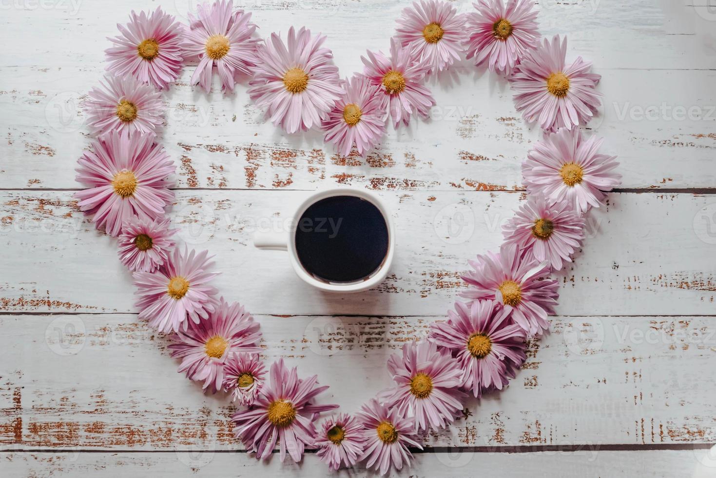 Flowers composition. Heart symbol made of pink flowers and leaves. Top view, flat lay photo