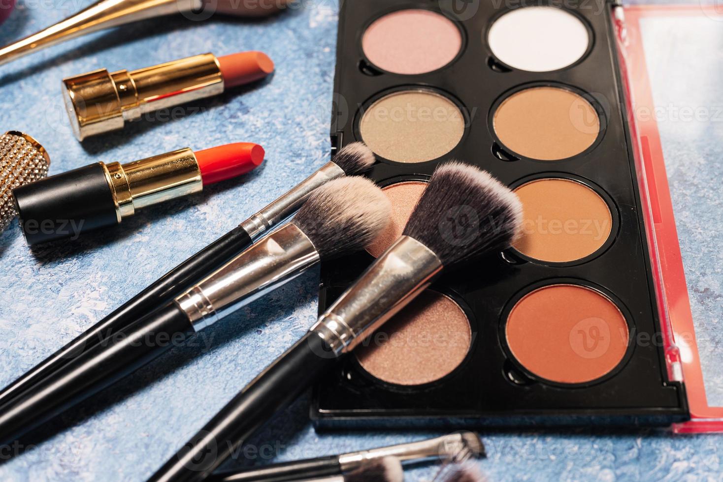 Various makeup products, brushes on blue background photo