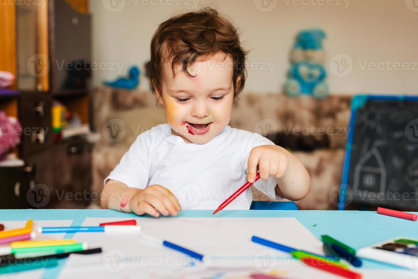 un niño feliz y alegre dibuja con un rotulador en un álbum usando una variedad de herramientas de dibujo. foto