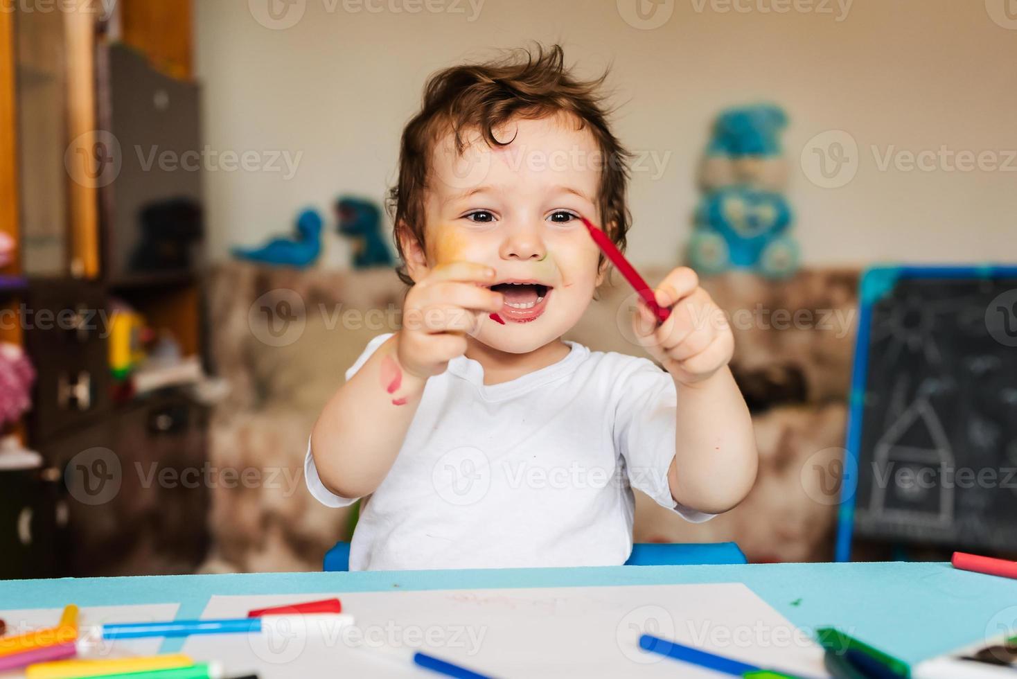 un niño feliz y alegre dibuja con un rotulador en un álbum usando una variedad de herramientas de dibujo. foto