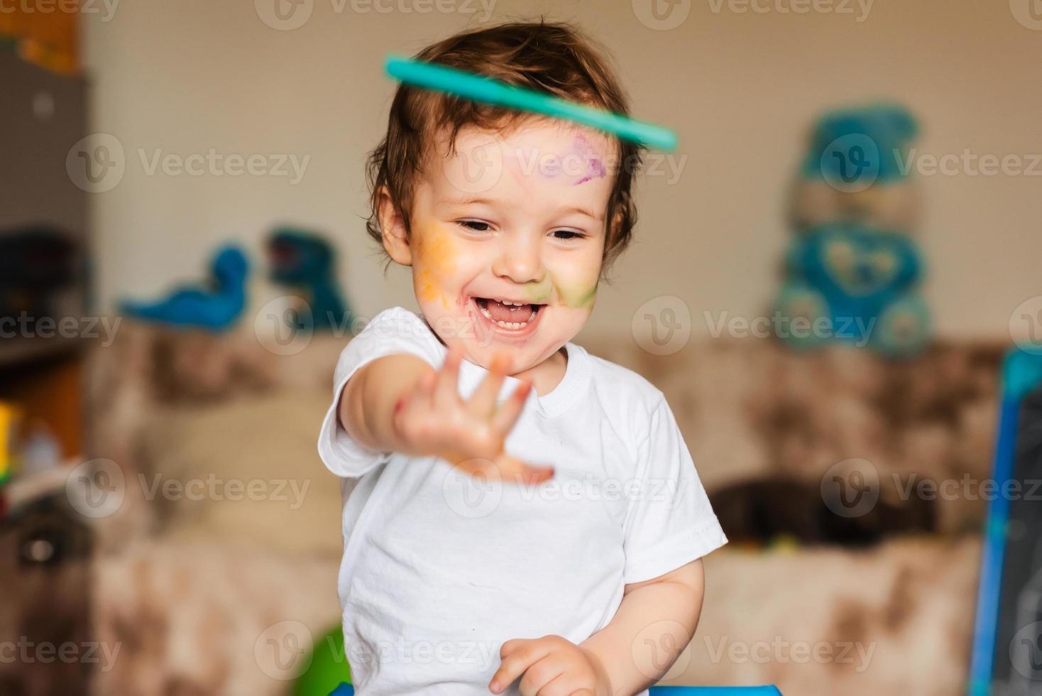 a little boy plays with colorful markers on a piece of paper photo