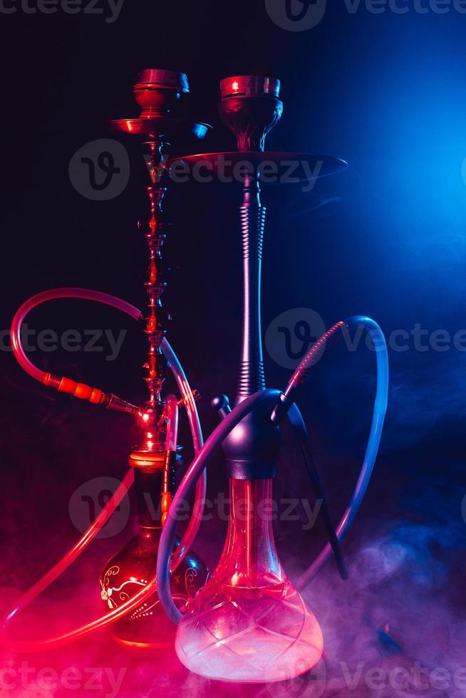 cachimba moderna, shisha sobre un fondo negro ahumado con luces de neón foto