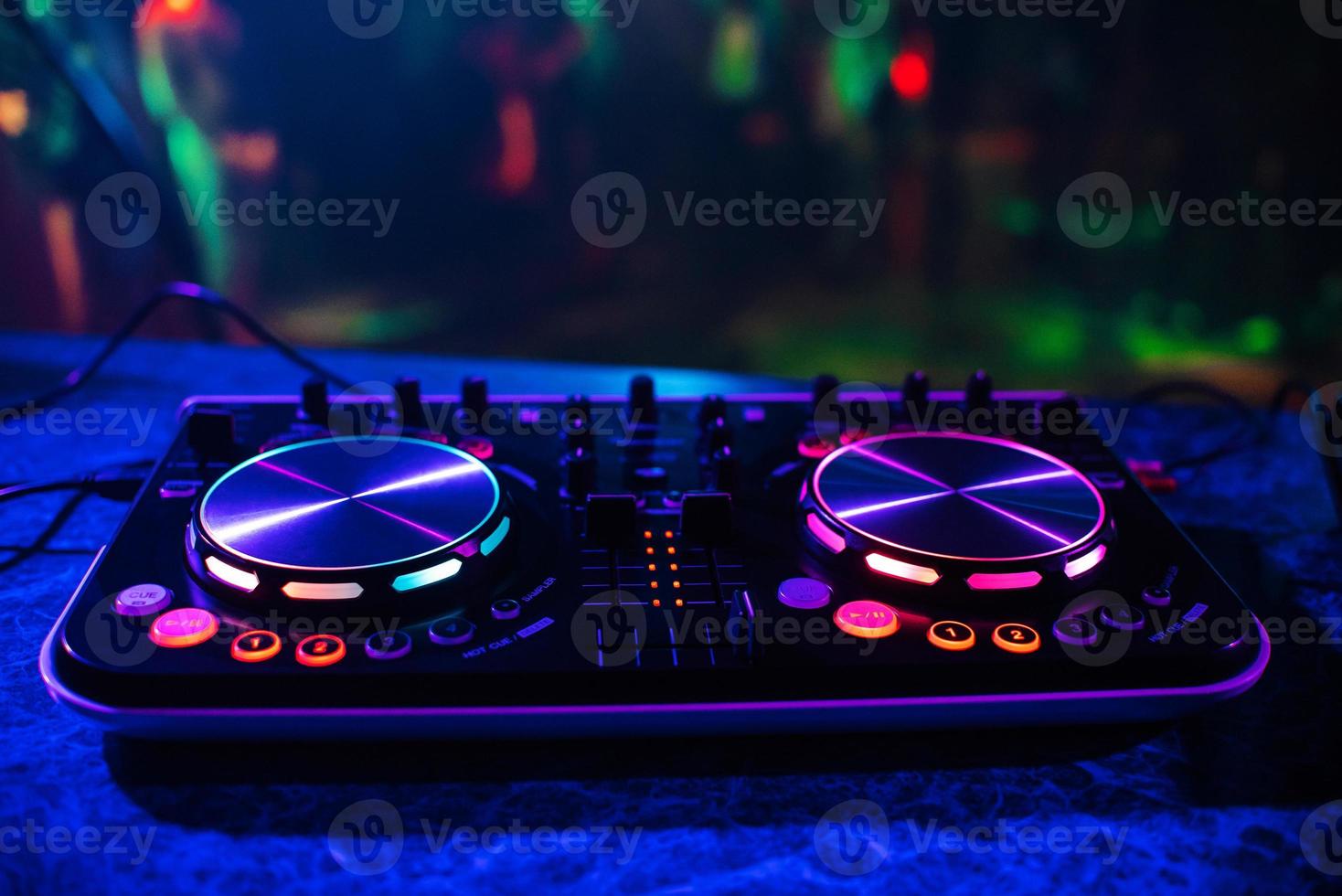 DJ console for mixing music with blurry people dancing at a nightclub party photo