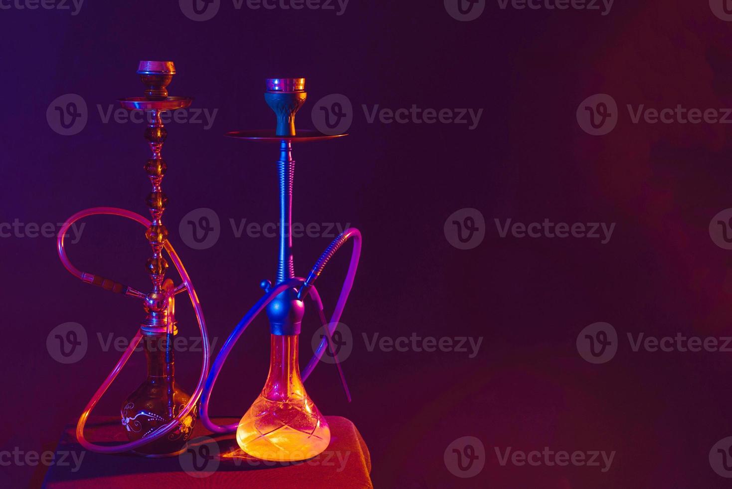 Modern hookah, shisha on a black background with colored lighting and smoke. Place for your text photo