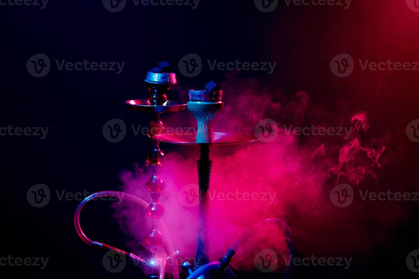 tazón de narguile, shisha y carbones sobre un fondo negro ahumado con iluminación de colores foto