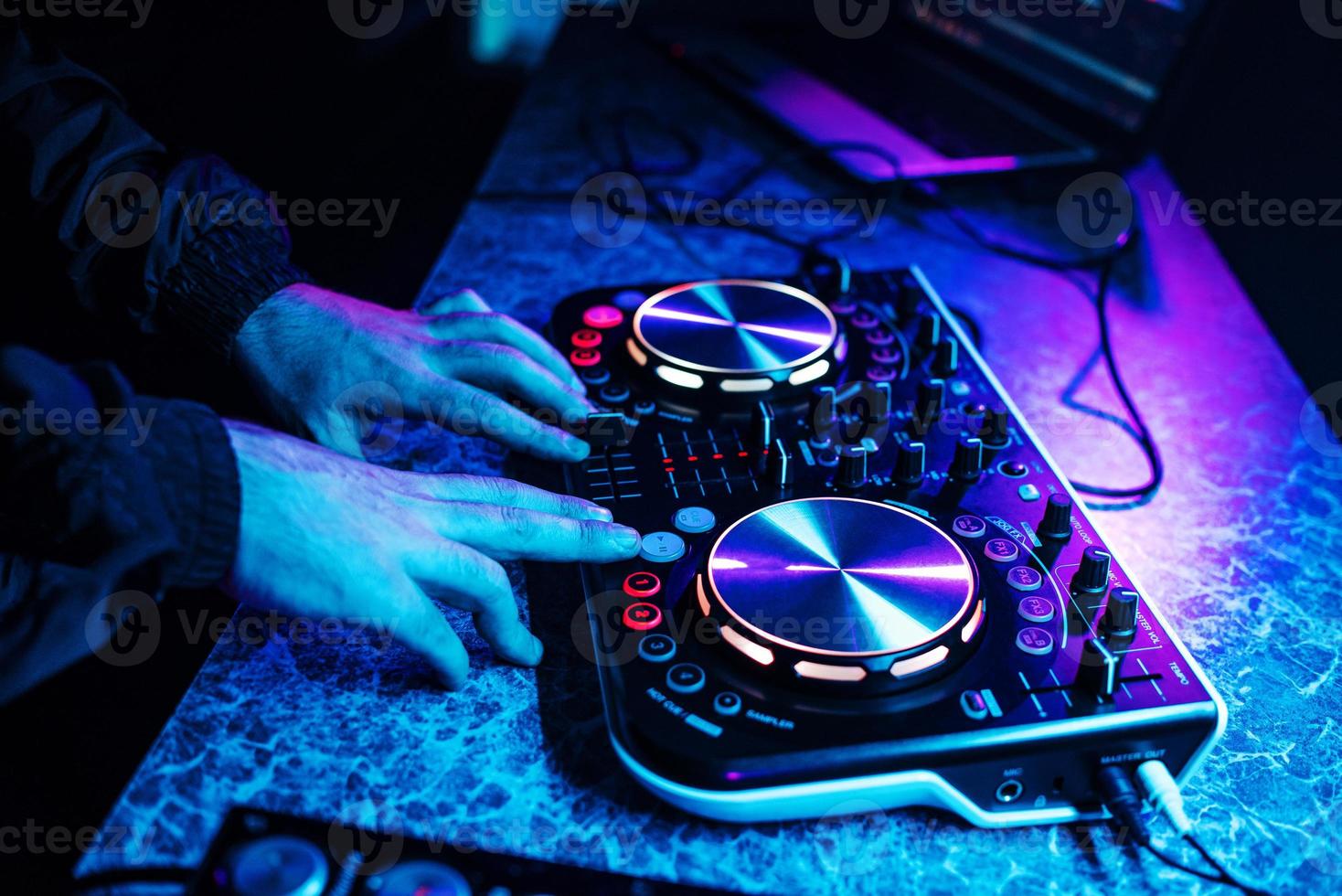 DJ console for mixing music with hands and with blurred people dancing at a night club party photo