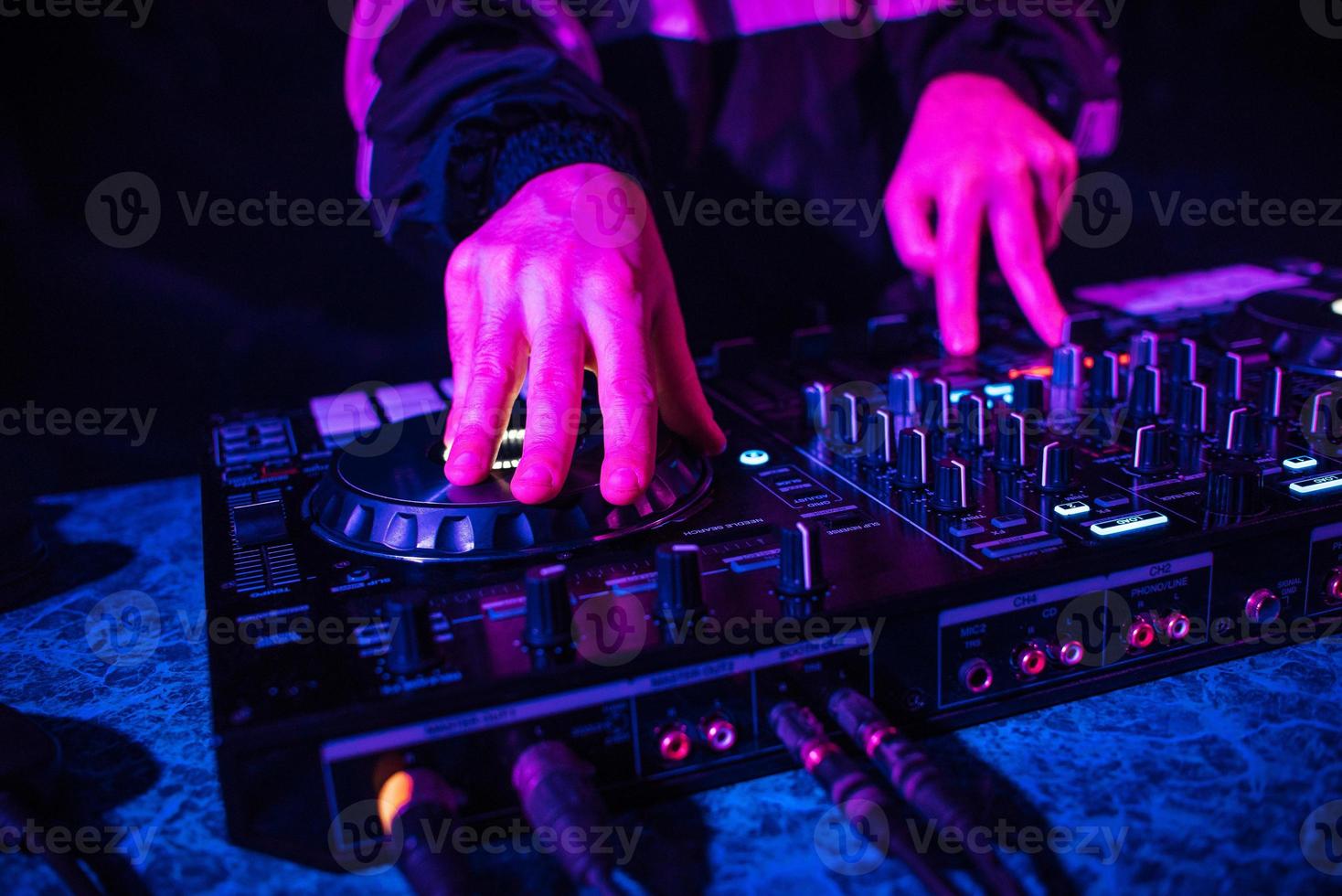 consola de dj para mezclar música con las manos y con gente borrosa bailando en una fiesta nocturna foto