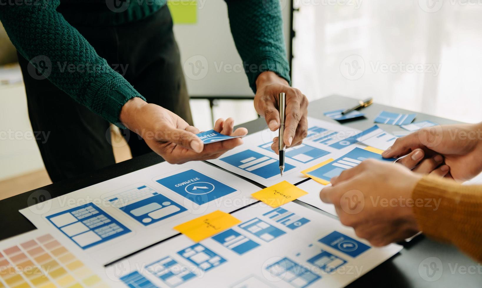 UX developer and ui designer brainstorming about mobile app interface wireframe design with customer breif and color code at office. photo