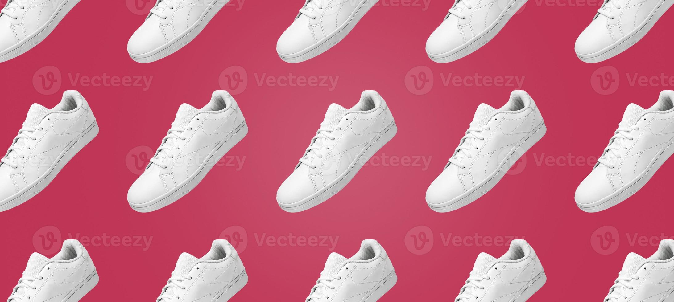 Banner pattern of white sneakers isolated on Viva Magenta background. Sportive pair of shoes for mockup. Fashionable stylish sports casual shoes. Modern and minimalist wallpaper. photo