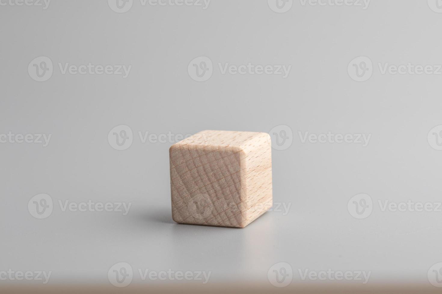 Simple empty wooden dice, one blank cubes made of wood with one central element, gray background. Copy space, logo space in the middle. photo