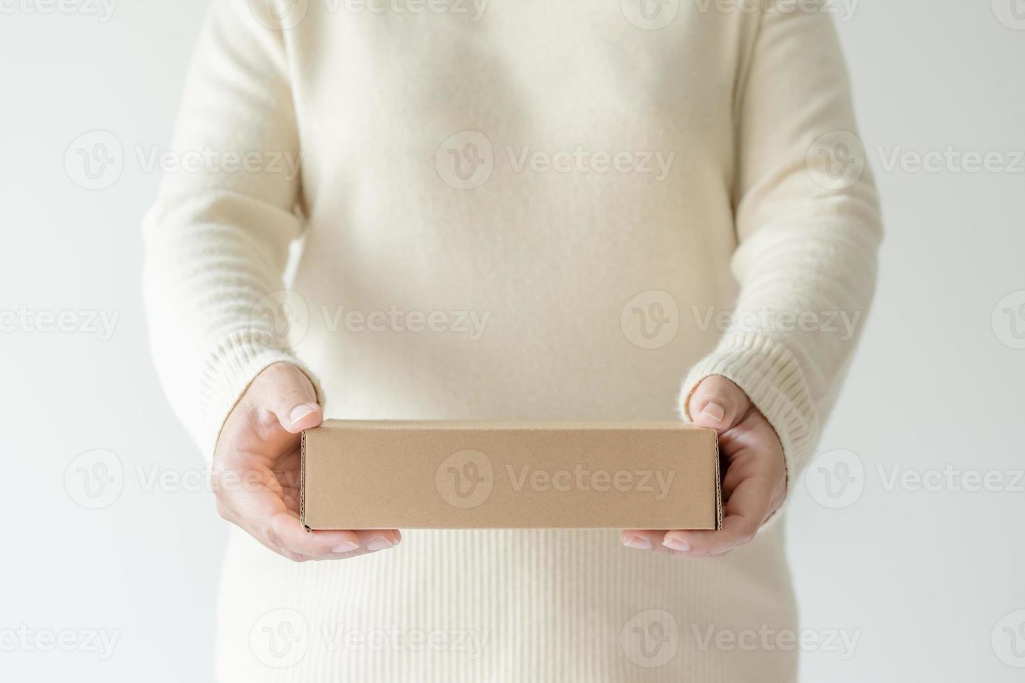 Woman hands carrying brown cardboard box. Concept of using recycle paper box. photo