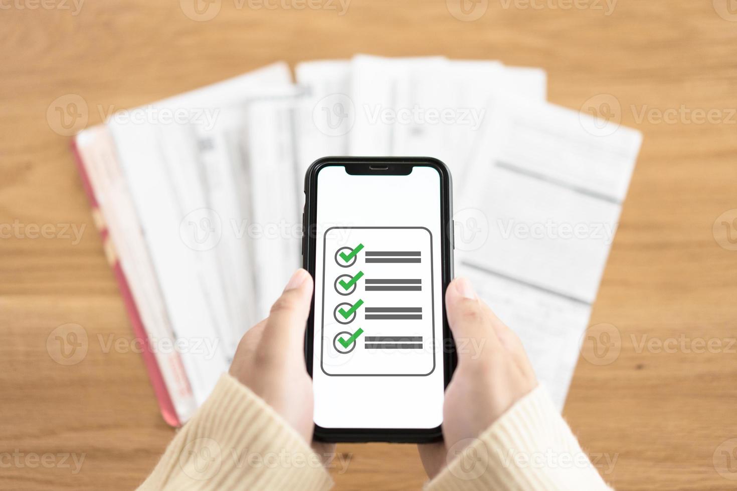 Expenses checklist for payment on the screen of mobile phone. Woman hands holding phone showing list of what have been paid. photo