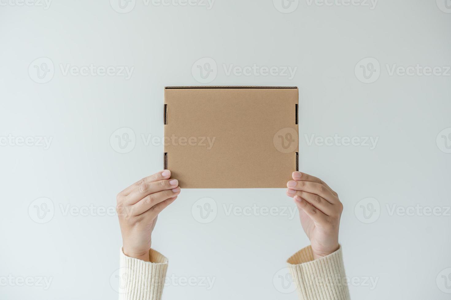 Woman hands carrying brown cardboard box. Concept of using recycle paper box. photo