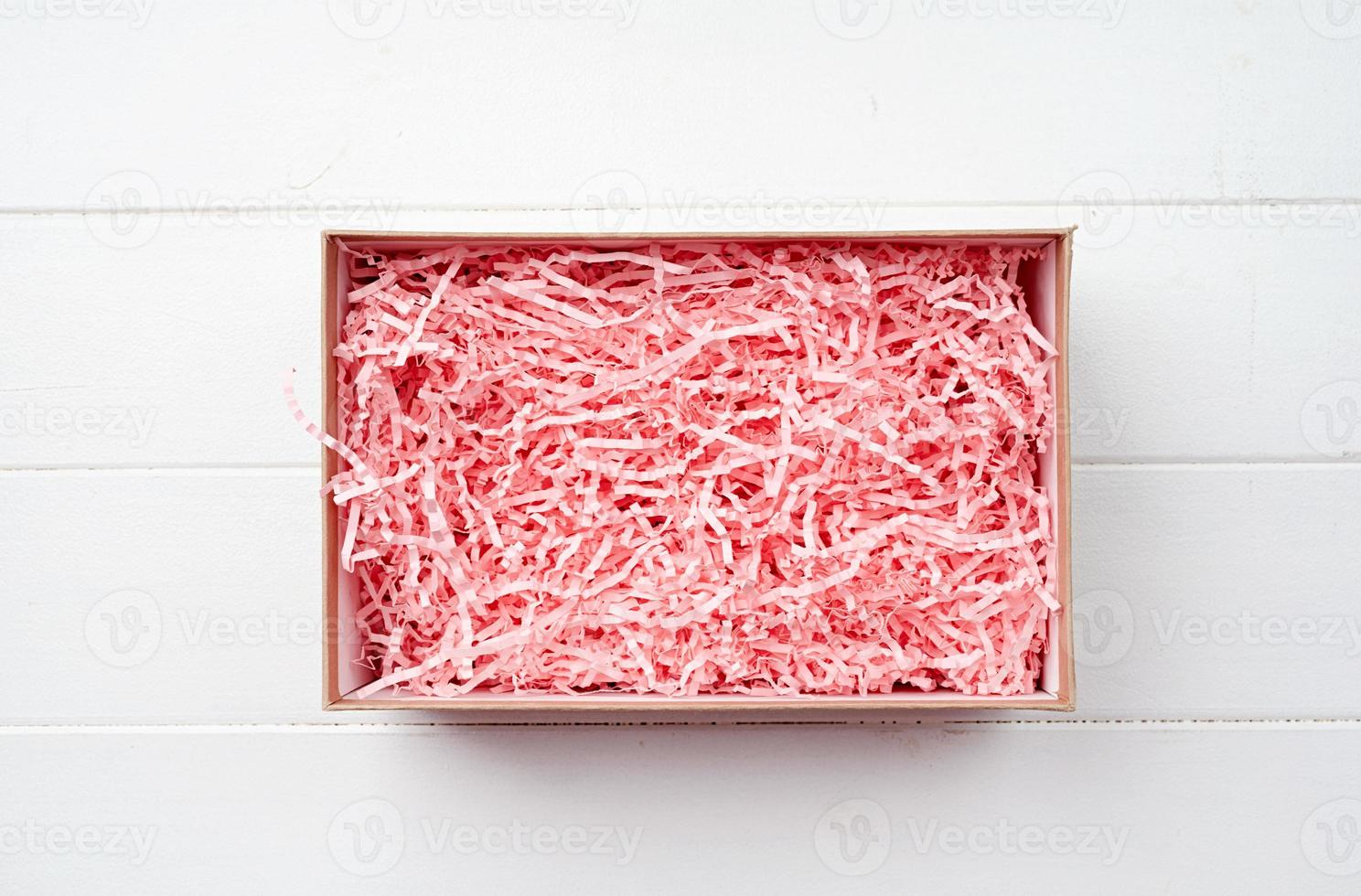 Shredded pink paper packing material texture in a craft box, mockup design photo