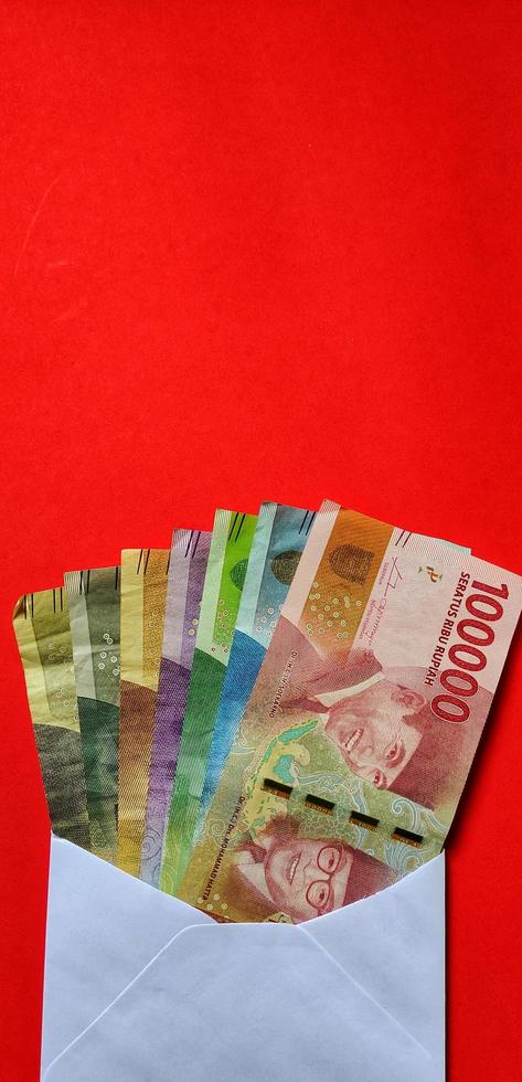Portrait of Indonesian Rupiah in white envelope isolated on red background. The concept of giving angpao on Chinese New Year photo
