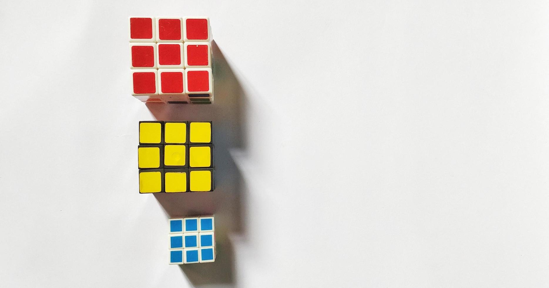 Jakarta, December 2022. Three rubik's cubes of different sizes and colors isolated on white background. Free space photo