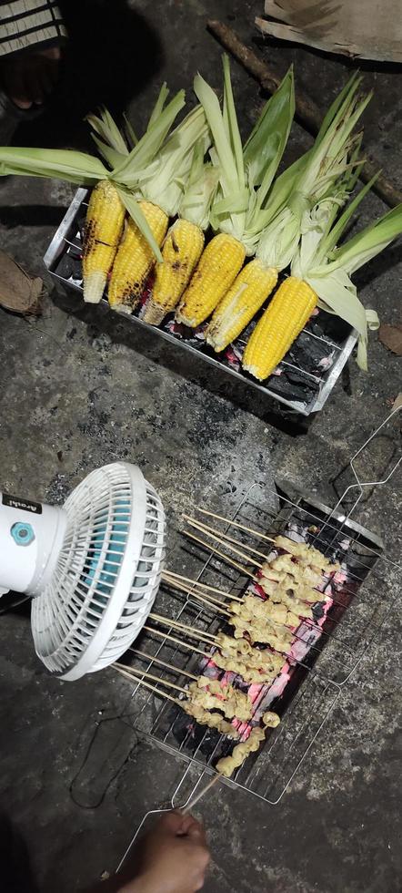Some chicken and corn skewers that have been seasoned and are being grilled, ready to be served photo