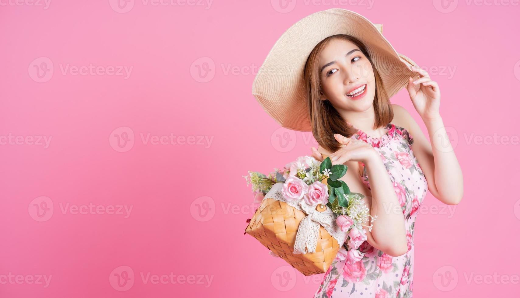 Photo of young Asian girl wearing flower dress on pink background