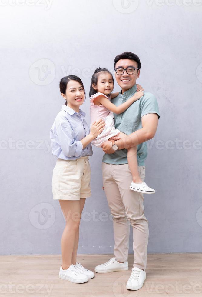 Young Asian family standing on background photo