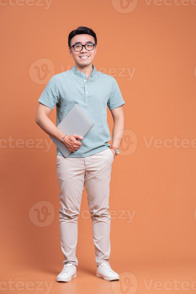 Full length image of young Asian man standing on backgound photo