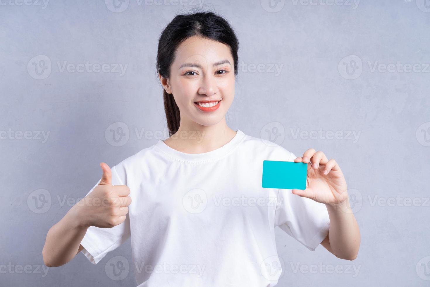 Image of young Asian woman holding bank card on background photo