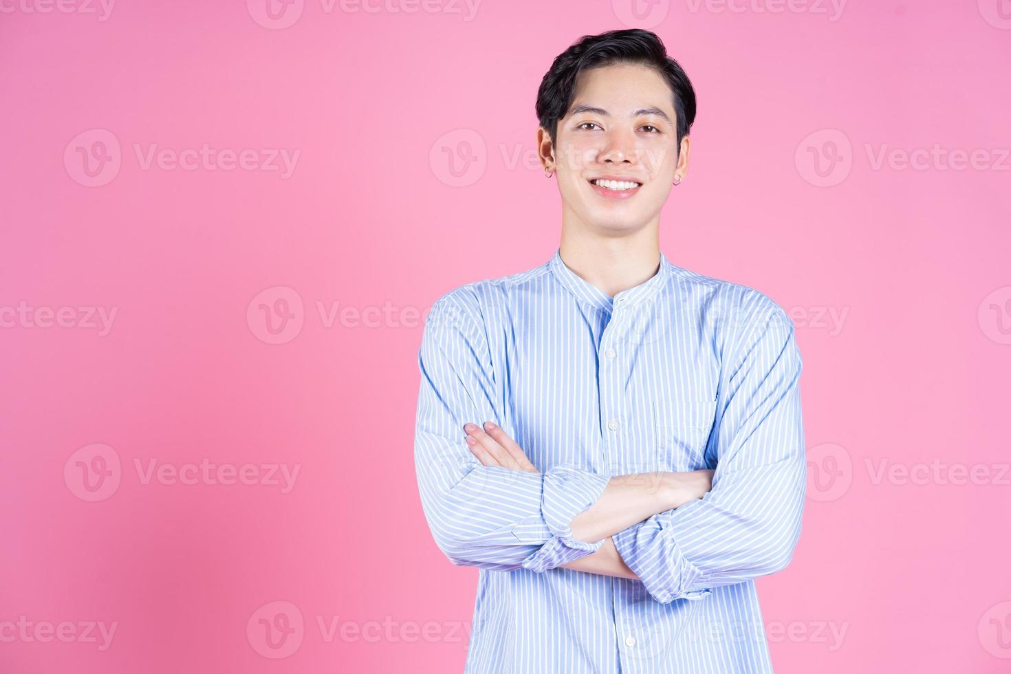 Portrait of young Asian man on pink background photo