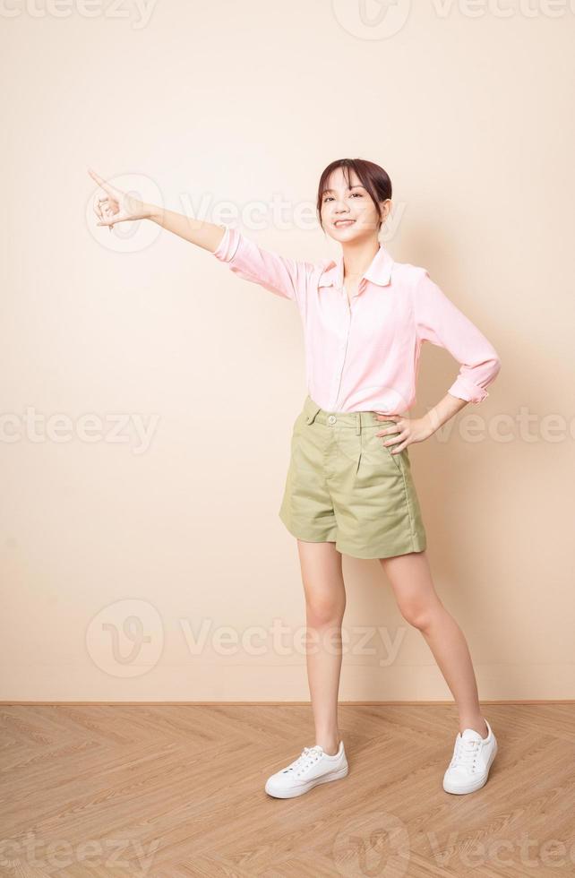 Full length photo of young Asian woman standing on background