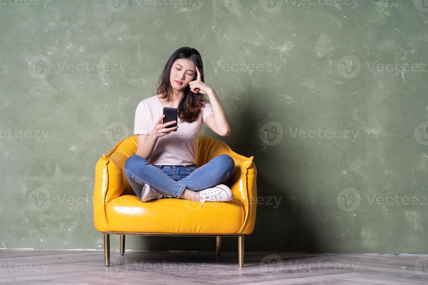 Image of beautiful young Asian woman sitting on yellow armchair photo