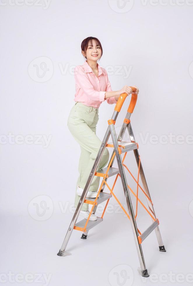 Image of young Asian woman clamb up to the ladder photo