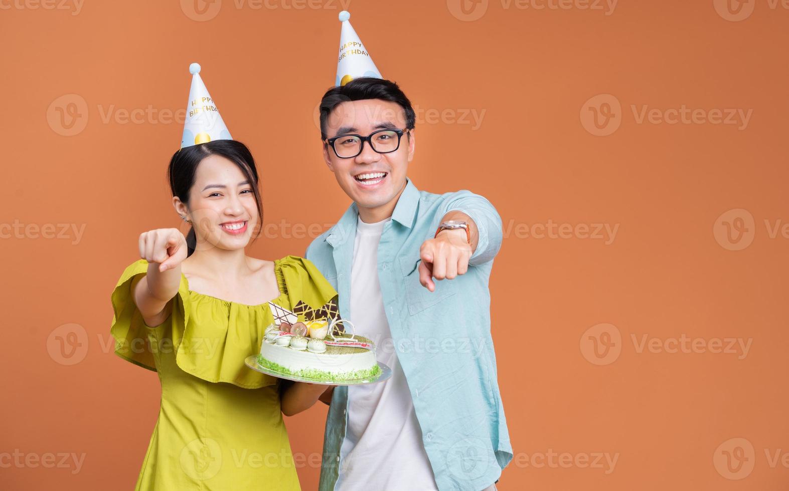joven pareja asiática sosteniendo pastel de cumpleaños en el fondo foto