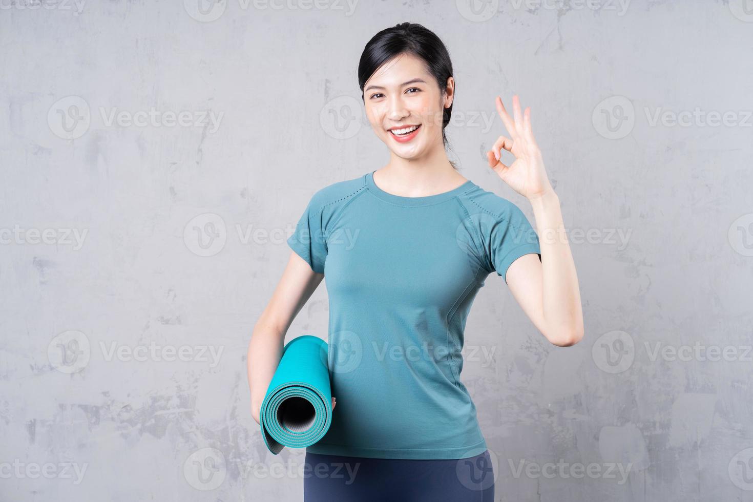 image of young Asian woman holding yoga carpet photo