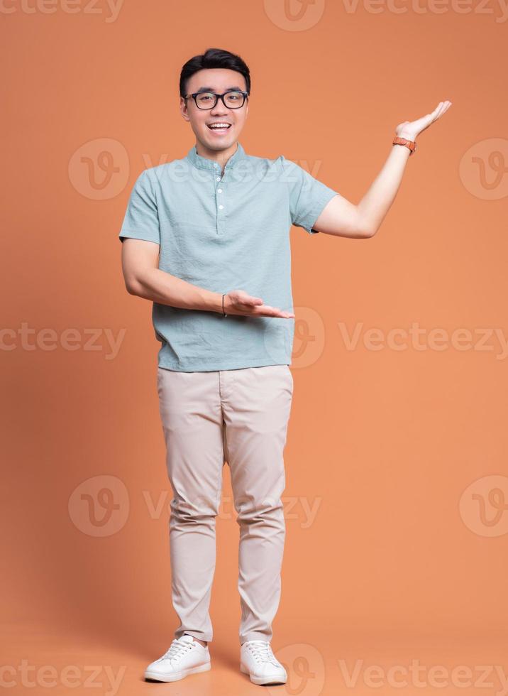 Full length image of young Asian man standing on backgound photo