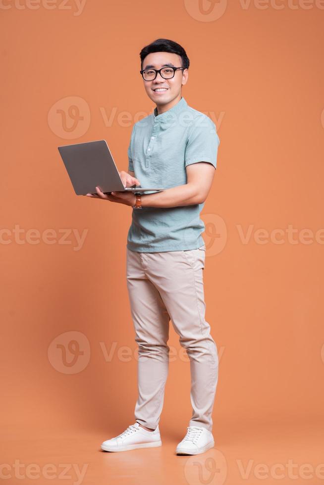 Full length image of young Asian man standing on backgound photo