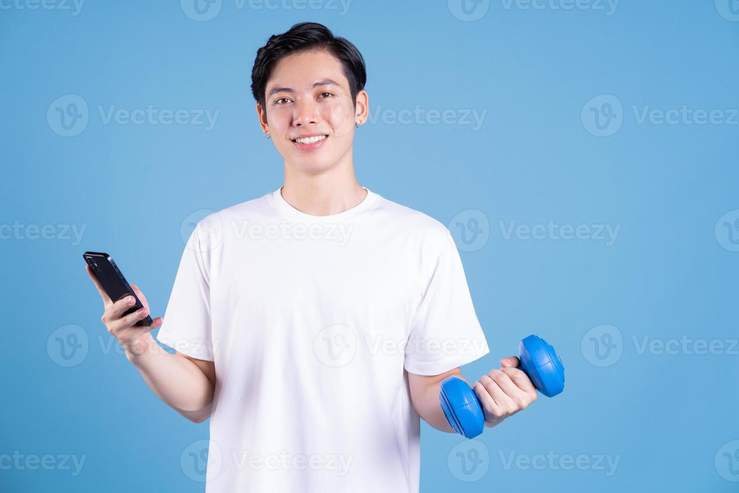 Young Asian man holding dumbbell on background photo