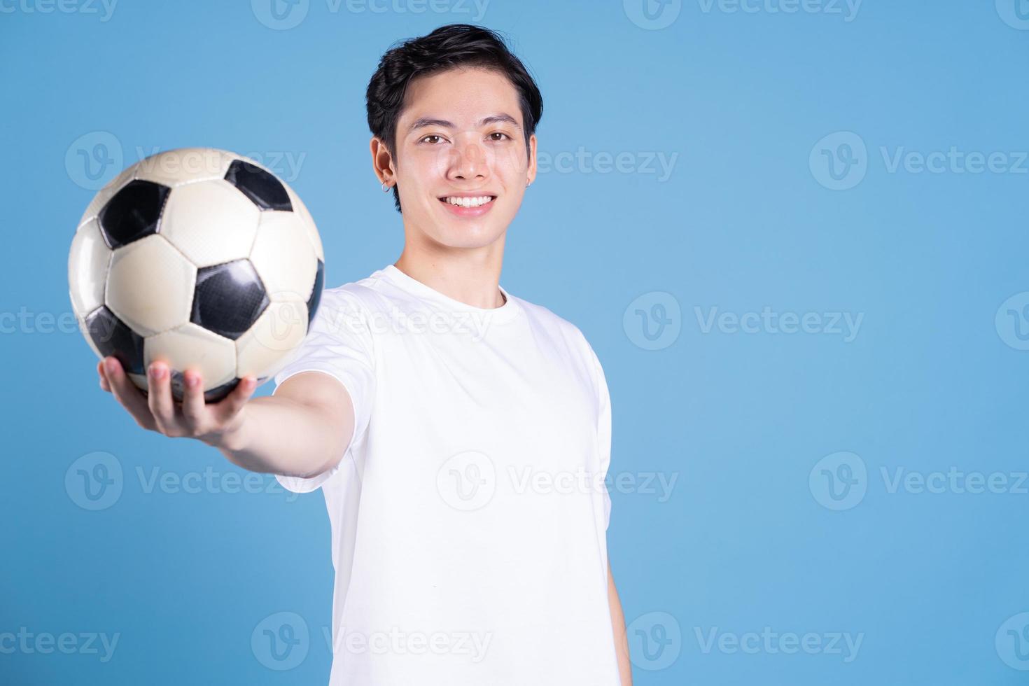 joven asiático sosteniendo la pelota en el fondo foto