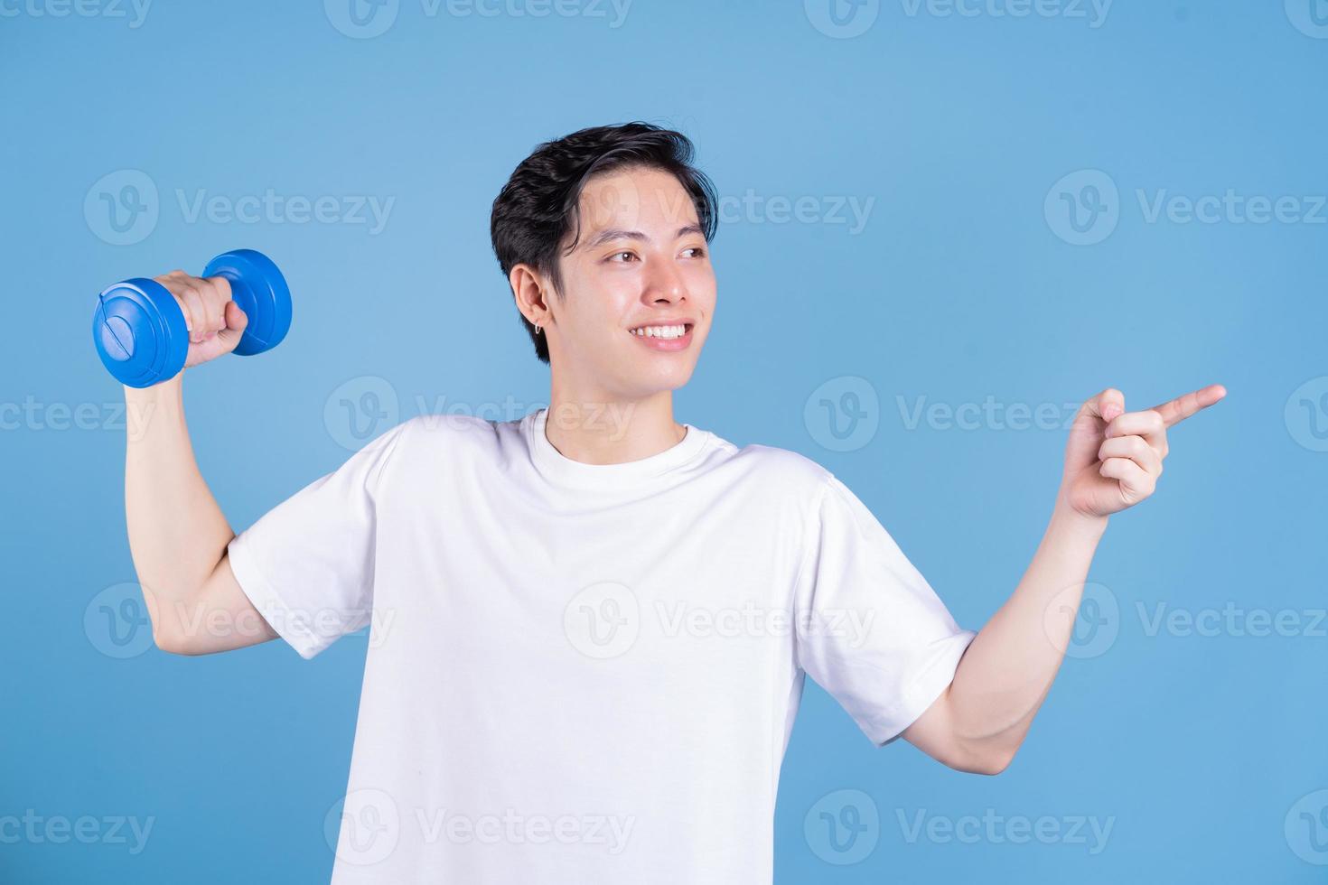 Young Asian man holding dumbbell on background photo