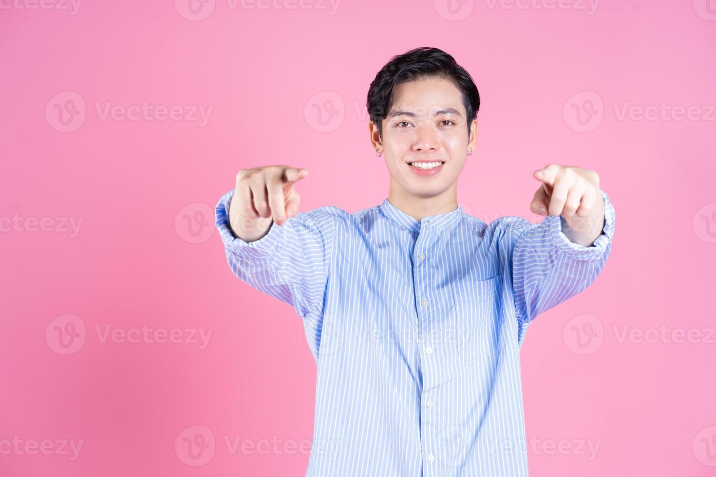 Portrait of young Asian man on pink background photo