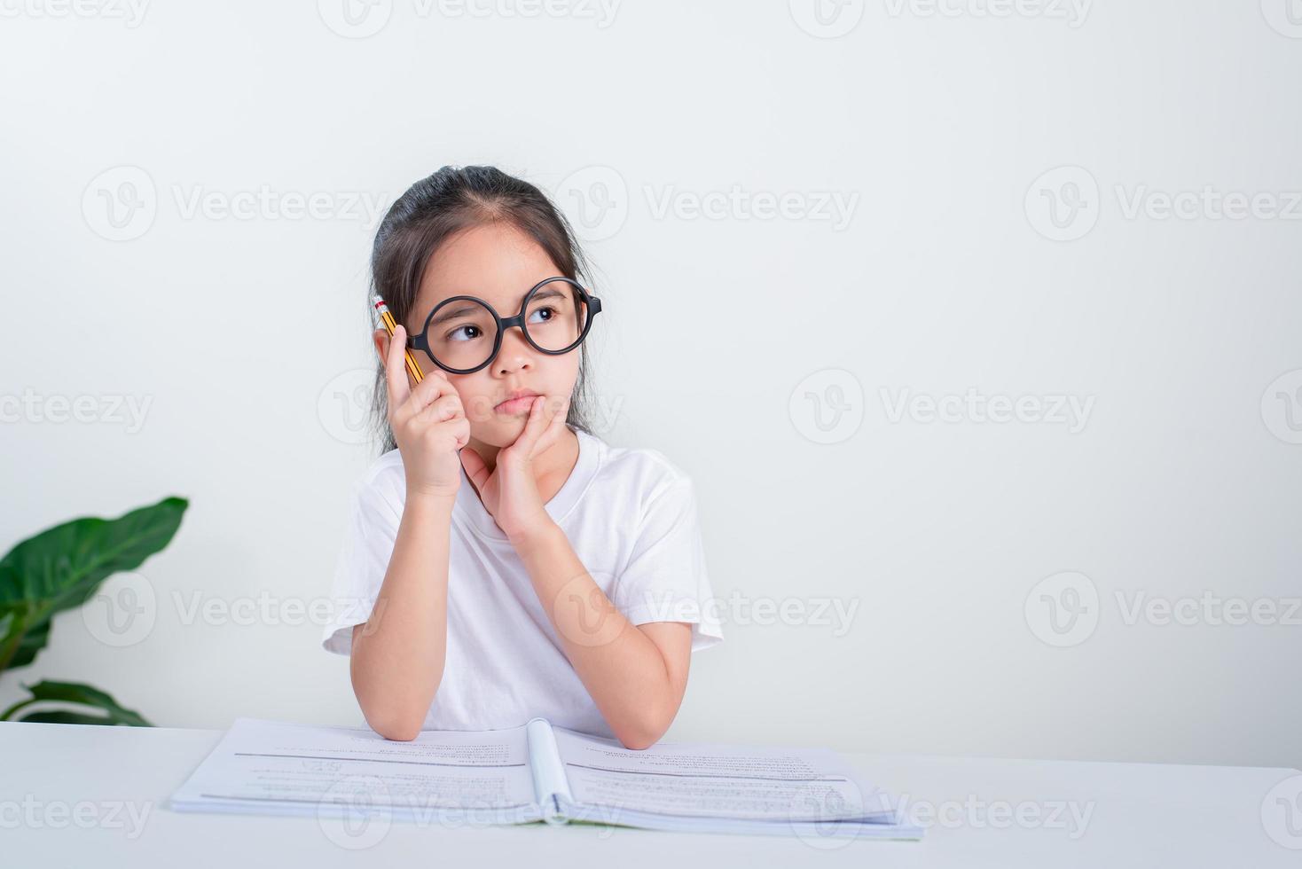 Portrait of little pupil writing at desk in  Student girl study doing test in primary school. Children writing notes in classroom. Education knowledge concept photo
