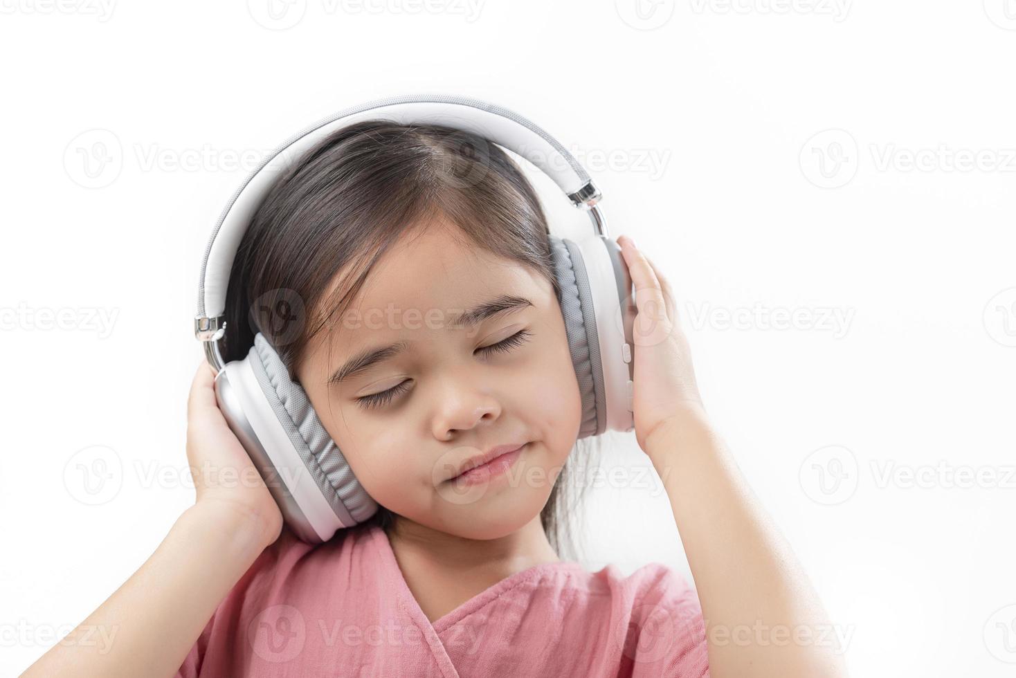 una niña hermosa asia poniendo el auricular aislado en un fondo blanco. foto