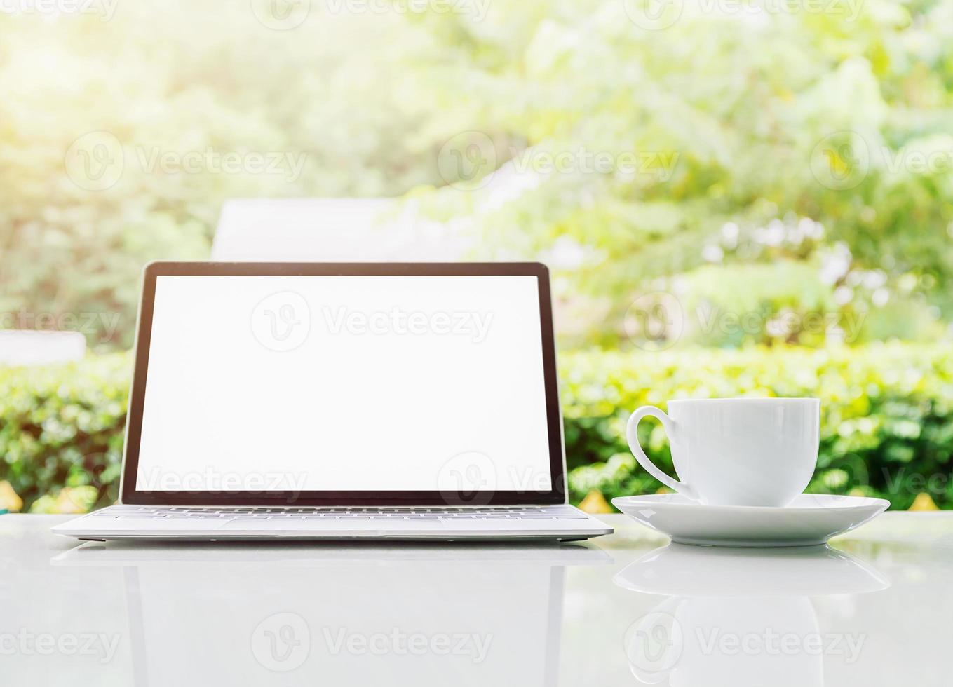 Laptop computer and cup of coffee on the table in morning photo